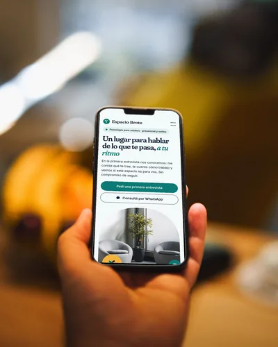 Landing de un espacio de psicología con reservas abierta en un celular que sostiene una mano