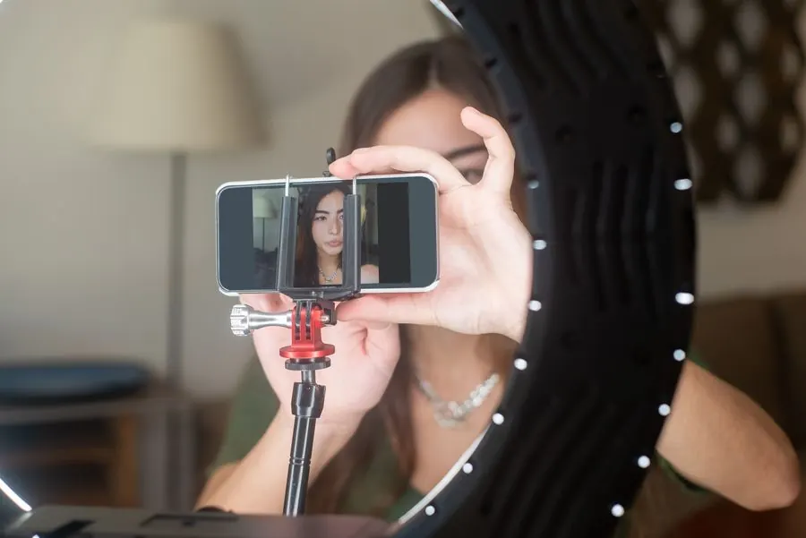 Una chica acomoda el celular en un soporte frente a un aro de luz